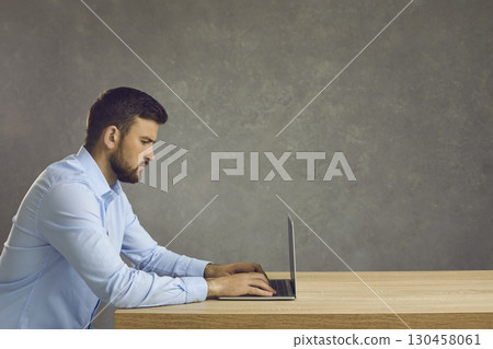 Serious focused smart programmer or employee working with laptop on deadline project. 130458061