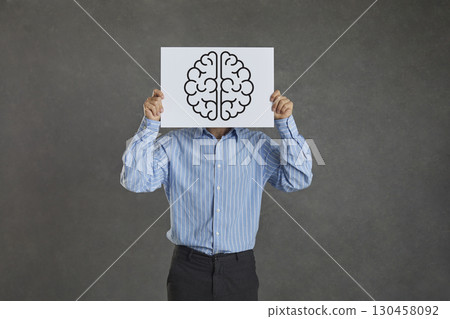Creative man covers his face with a sheet of paper with a picture of a human brain 130458092