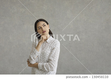 Woman thinking over question, considering choices, imagining something on copy space background 130458110