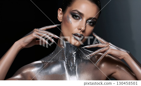 Futuristic model with chrome silver paint and metallic nails in dramatic light Futuristic model with chrome silver paint and metallic nails in dramatic light 130458501
