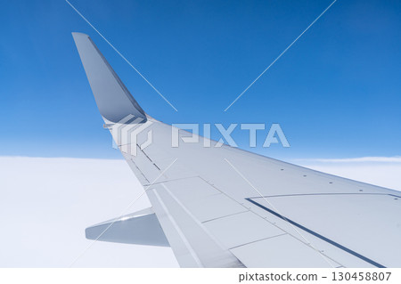 Wing of an airplane flying overhead 130458807