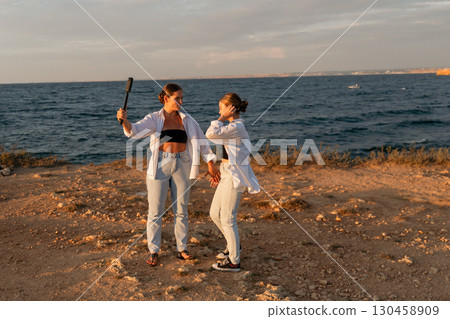 Women Selfie Beach Sunset - Two women take a selfie on a beach at sunset. 130458909