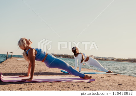 Yoga, Beach, Women: Two women practicing yoga on a pier at the beach during a sunny day. Yoga, Beach, Women: Two women practicing yoga on a pier at the beach during a sunny day. 130458952