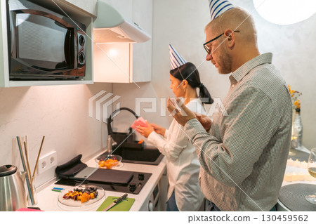 Couple Kitchen Birthday Party: Celebrating intimate birthday, cooking meal, modern apartment kitchen. 130459562