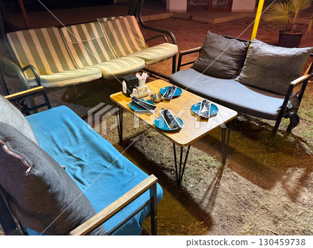 Cafe terrace with sofas and table set for guests in the evening. Hospitality, service, leisure environment, social atmosphere and outdoor comfort. 130459738