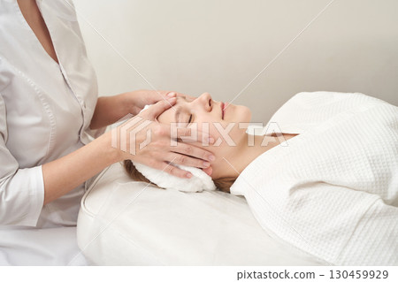 Young caucasian female relaxing during professional spa facial massage session 130459929