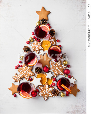 Christmas tree arrangement with cookies, mulled wine, oranges, pinecones, and baubles on white background. Festive creative holiday food composition. Christmas tree arrangement with cookies, mulled wine, oranges, pinecones, and baubles on white background. Festive creative holiday food composition. 130460067