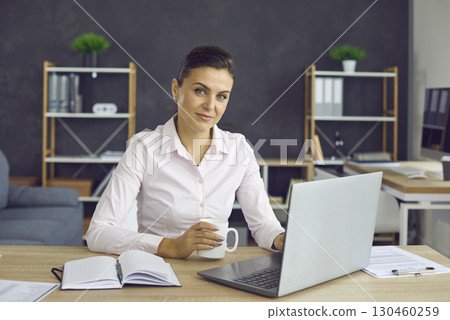 Portrait of a businesswoman drinking coffee or tea at work during a break in the office. 130460259