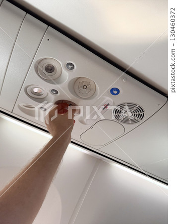 Male hand adjusting air vent in airplane cabin. Passenger comfort, aviation technology, and travel experience. 130460372
