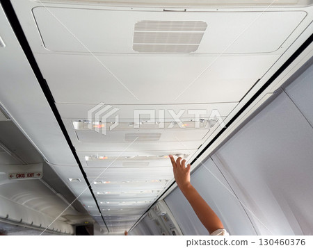 Male hand adjusting air vent in airplane cabin. Passenger comfort, aviation technology, and travel experience. 130460376