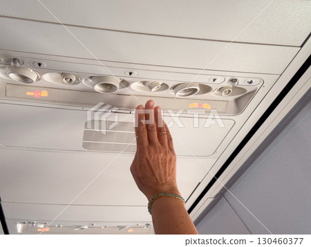 Male hand adjusting air vent in airplane cabin. Passenger comfort, aviation technology, and travel experience. 130460377