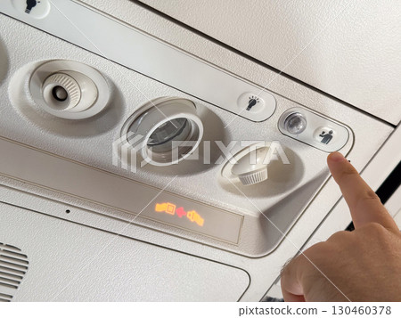 Airplane passenger pressing the flight attendant call button. Communication, service, and assistance during air travel. Airplane passenger pressing the flight attendant call button. Communication, service, and assistance during air travel. 130460378