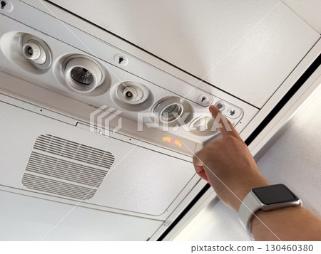 Airplane passenger pressing the flight attendant light button. Communication, service, and assistance during air travel. Airplane passenger pressing the flight attendant light button. Communication, service, and assistance during air travel. 130460380