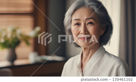 Confident elderly Asian lady in white blouse with soft natural light 130461102
