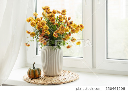 Bouquet of autumn orange flowers and pumpkin on windowsill. 130461206