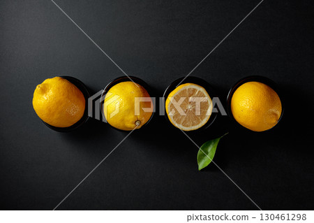 Fresh, juicy lemons in small black bowls on a black background. Fresh, juicy lemons in small black bowls on a black background. 130461298
