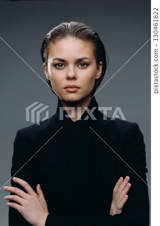 Serious woman in black clothes with crossed arms and confident expression Serious woman in black clothes with crossed arms and confident expression 130461622