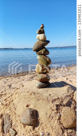 On the beach, on the sand, pebbles are placed on top of each other 130461811
