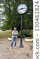 a man stands beside the clock in the square 130461824