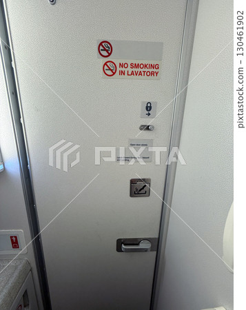 Lavatory door with no smoking sign inside airplane cabin interior. Aviation safety, hygiene facility and airline regulation during passenger air travel. 130461902