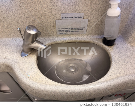 Airplane lavatory sink with faucet, soap dispenser, and towels. Hygiene, compact facilities, and airline service ensure passenger comfort and aviation travel. Airplane lavatory sink with faucet, soap dispenser, and towels. Hygiene, compact facilities, and airline service ensure passenger comfort and aviation travel. 130461924