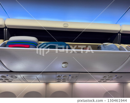 Overhead storage bins inside airplane cabin with luggage and personal items secured for travel. Aviation, mobility, and tourism lifestyle highlighting preparation, safety, and passenger journey. Overhead storage bins inside airplane cabin with luggage and personal items secured for travel. Aviation, mobility, and tourism lifestyle highlighting preparation, safety, and passenger journey. 130461944