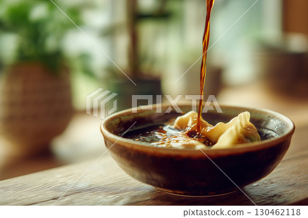Dumpling delicately dipped in savory soy sauce during a cozy afternoon 130462118
