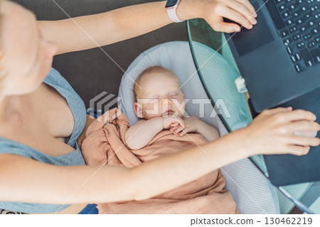 Multitasking mom works on a laptop at home while her newborn baby sleeps peacefully in a cozy baby nest on her lap. Concept of remote work, motherhood, and balancing family and career 130462219