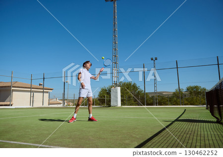 Young Athlete Practicing Tennis on Outdoor Court Under Clear Sunny Skies Young Athlete Practicing Tennis on Outdoor Court Under Clear Sunny Skies 130462252