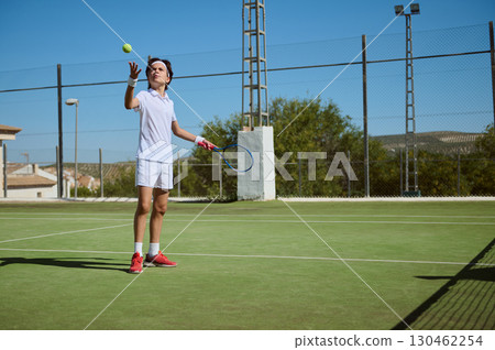 Young Athlete Practicing Tennis on an Outdoor Court on a Sunny Day 130462254