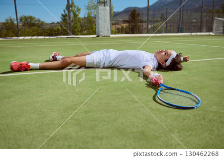 Young Tennis Player Lying Exhausted on the Court After Intense Match 130462268
