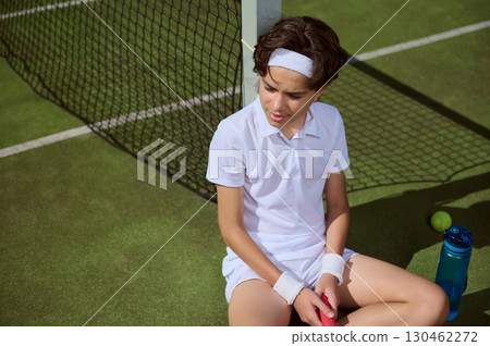 Young Tennis Player Resting on Court During a Sunny Day 130462272