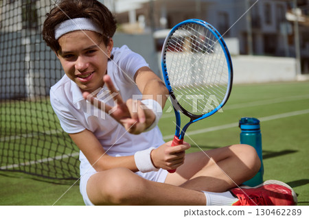 Young Tennis Player Posing with Racket on Outdoor Court in Relaxed Mood 130462289