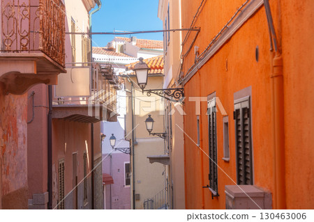 Narrow European alleyway lined with vibrant, colorful historic buildings. Traditional street lamps hang between the buildings. The vivid facades highlight architectural charm Narrow European alleyway lined with vibrant, colorful historic buildings. Traditional street lamps hang between the buildings. The vivid facades highlight architectural charm 130463006