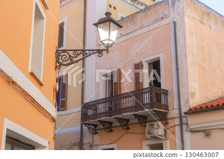Mediterranean-style building facade featuring a decorative wrought iron balcony and vintage street lamp. The pastel tones and architectural details create a quaint, timeless atmosphere Mediterranean-style building facade featuring a decorative wrought iron balcony and vintage street lamp. The pastel tones and architectural details create a quaint, timeless atmosphere 130463007