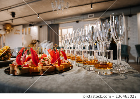 Luxury banquet table with whiskey, champagne flutes, and gourmet appetizers at event Luxury banquet table with whiskey, champagne flutes, and gourmet appetizers at event 130463022