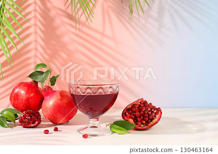 Red pomegranate wine and grains with ripe pomegranates on a trendy table with palm shades, concept festive party, advertising for a bar and cafe. Source of vitamins for a healthy lifestyle, Red pomegranate wine and grains with ripe pomegranates on a trendy table with palm shades, concept festive party, advertising for a bar and cafe. Source of vitamins for a healthy lifestyle, 130463164
