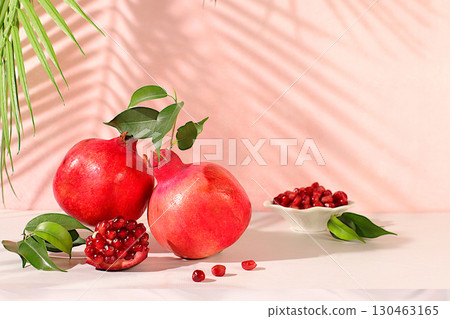 Modern still life with ripe pomegranates on a trendy table in the shade of palm trees, holiday party concept, bar and cafe advertising. Source of vitamins for a healthy lifestyle, autumn banner Modern still life with ripe pomegranates on a trendy table in the shade of palm trees, holiday party concept, bar and cafe advertising. Source of vitamins for a healthy lifestyle, autumn banner 130463165