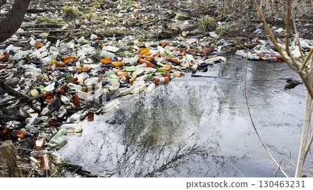 Dirty river is polluted with many plastic bottles. A lot of trash is dumped in open and freely available places at nature. Global environmental pollution problem. Concept of ecological disaster Dirty river is polluted with many plastic bottles. A lot of trash is dumped in open and freely available places at nature. Global environmental pollution problem. Concept of ecological disaster 130463231