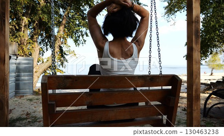 Happy woman ride on swing at tropical at sea beach. Carefree lady enjoying rest near ocean. Adult female having fun at sea shore on sunny day. Concept of summer vacation or holiday. Slow motion 130463238
