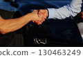 Male hand giving key of car to buyer of electric automobile outdoor. Handshake between salesman and new owner of modern auto after successful deal. Concept of buy or rent car. Slow mo 130463249