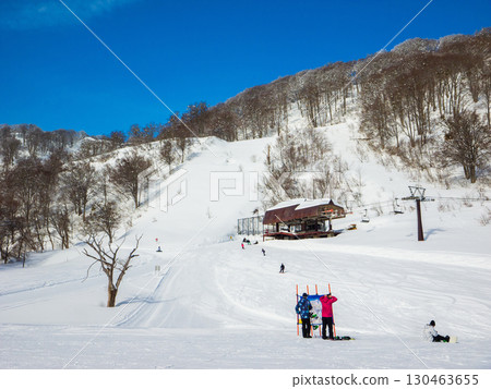 Snowboarders checking the slope map at the top of a ski resort on a clear day (Togari Onsen, Iiyama City, Nagano Prefecture) 130463655