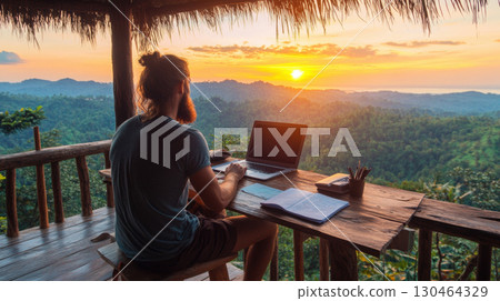 serene workspace with man working on laptop, surrounded by nature beauty at sunset 130464329