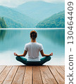 Peaceful yoga practice by serene lake surrounded by mountains 130464409