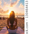 Meditative woman on beach at sunset, surrounded by people 130464413