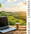 Laptop and coffee cup on outdoor desk with tropical farm view at sunrise 130464420