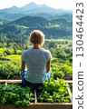 Person enjoys serene view of lush, green landscape from herb garden 130464423