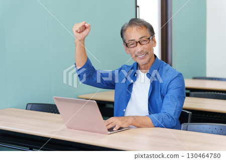 Senior man using a computer and making a fist pump Senior man using a computer and making a fist pump 130464780