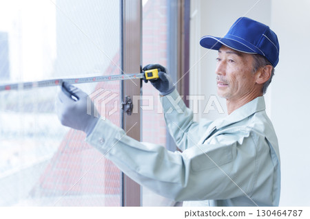 Interior construction worker measuring with a tape measure Interior construction worker measuring with a tape measure 130464787