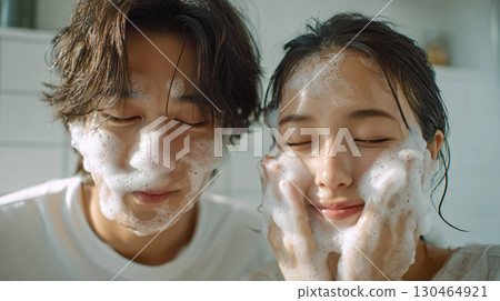Two men and women washing their faces in the bathroom at home, foaming facial cleanser, relaxing atmosphere in the morning 130464921